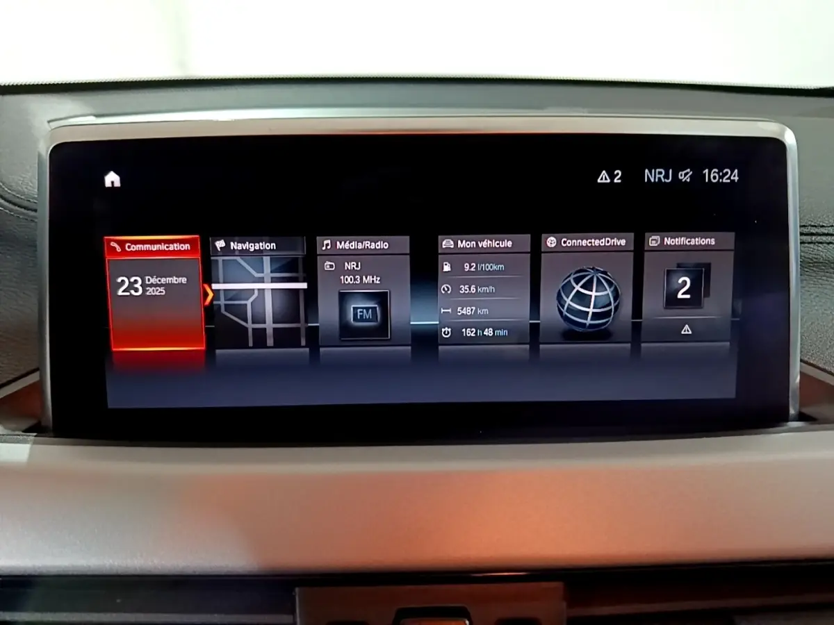 Écran central tactile du tableau de bord du BMW X2 noir, affichant navigation, radio et infos véhicule.