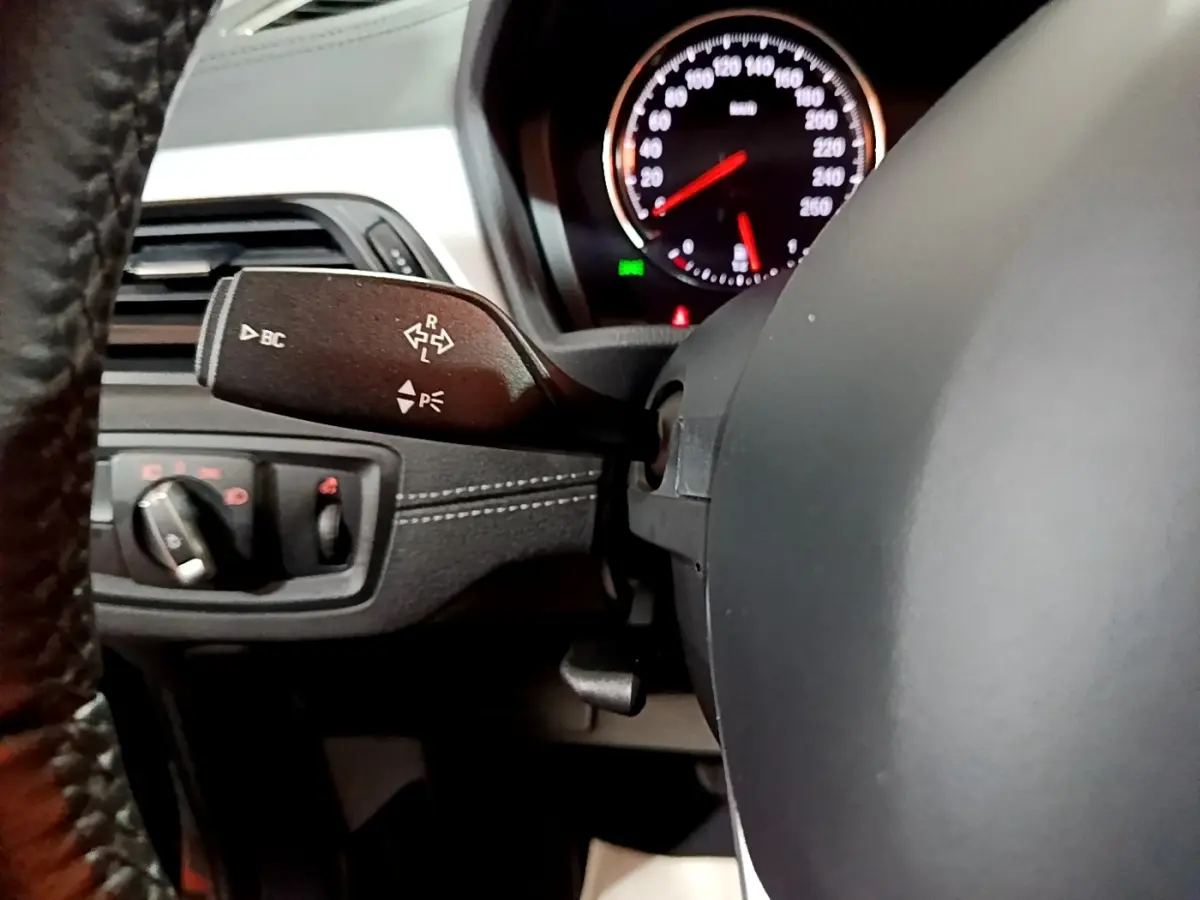 Gros plan intérieur sur le volant noir en cuir et la commande de clignotants du BMW X2 sDrive18i Lounge 2023.