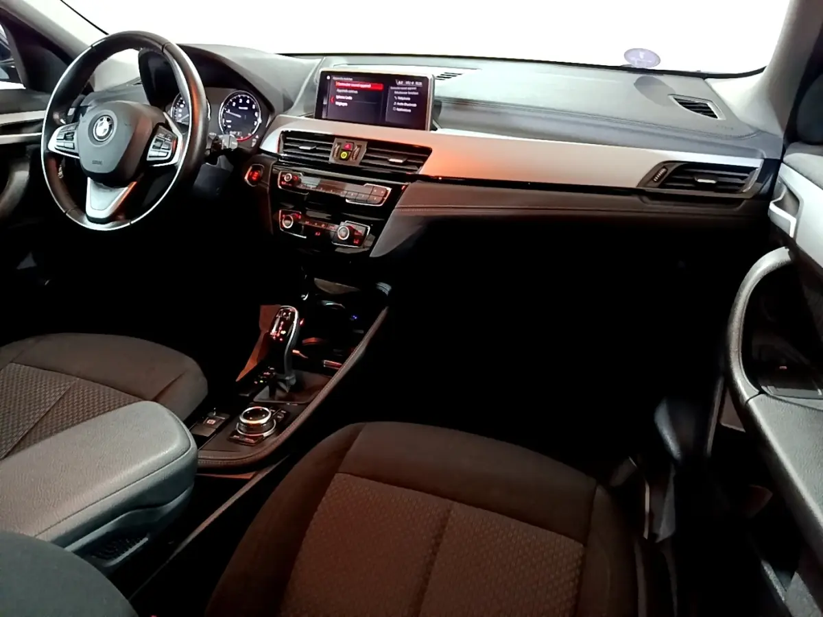 Vue intérieure avant droite du BMW X2 sDrive18i 2023, tableau de bord noir avec volant cuir alu multifonctions.