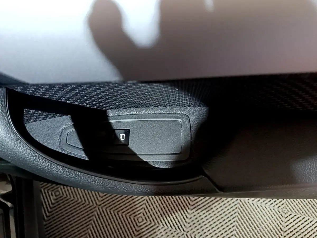 Bouton de commande de lève-vitre sur la porte intérieure côté gauche d'une BMW X2 noire 2023.