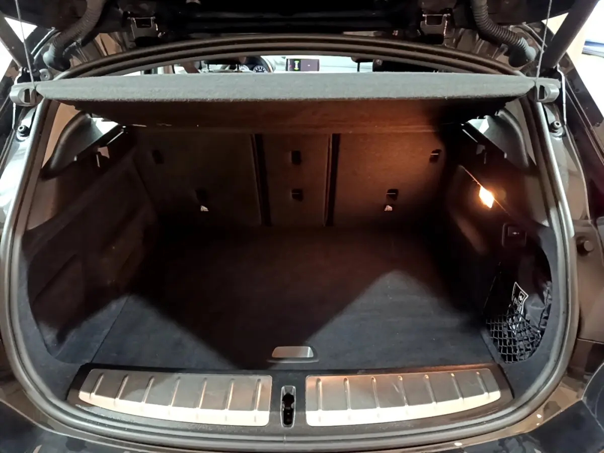 Coffre ouvert vu de l'arrière d'un BMW X2 noir, montrant un espace de chargement propre avec éclairage latéral.