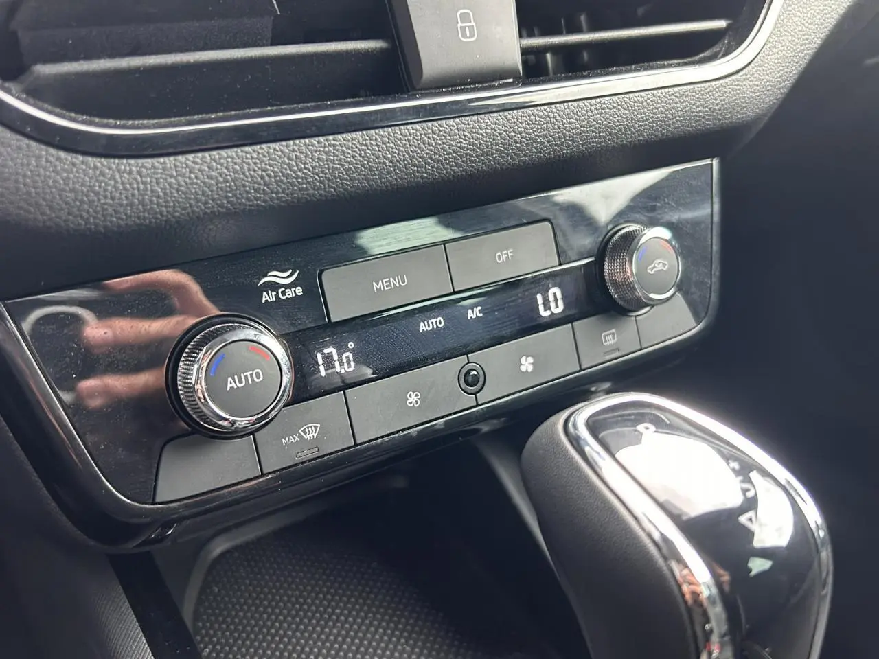 Gros plan sur la console centrale de la Skoda Scala blanche, montrant la climatisation automatique et le levier de vitesse chrome.