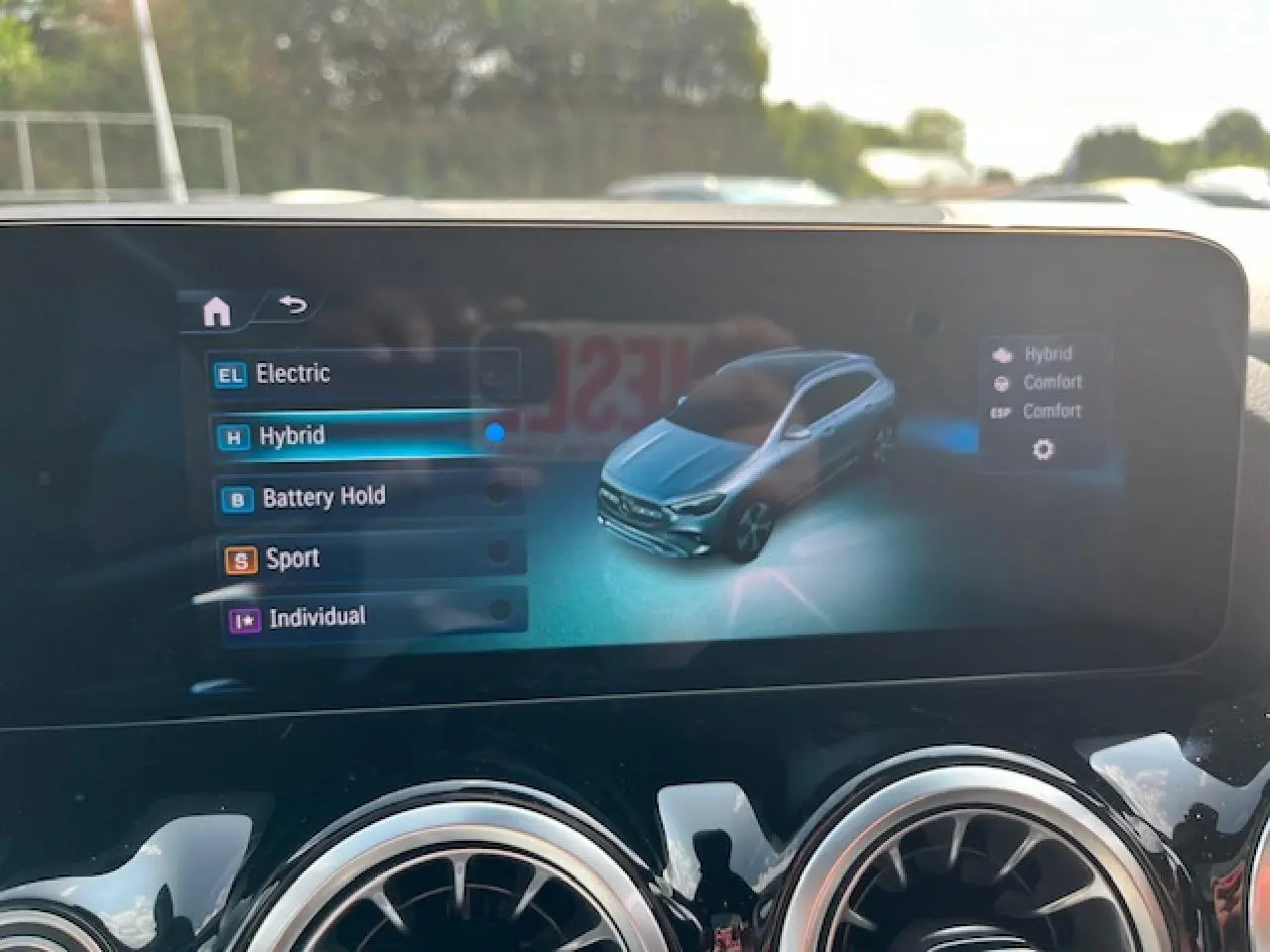 Écran central affichant les modes de conduite d'une Mercedes GLA 250 e hybride, vue 3/4 avant virtuelle grise.