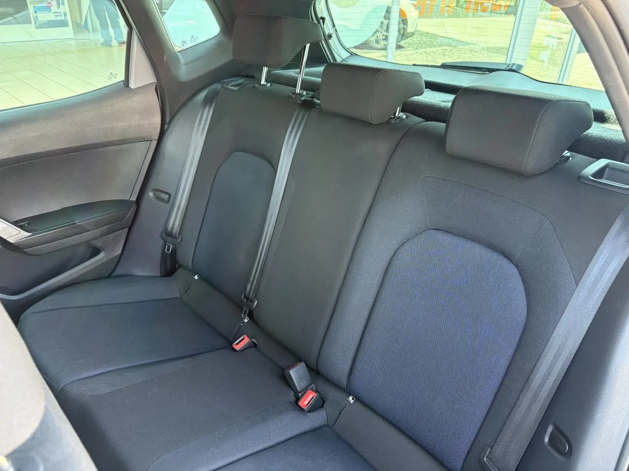 Vue intérieure du siège arrière textile noir de la SEAT ARONA 2024 avec appuie-têtes et ceintures visibles côté gauche.