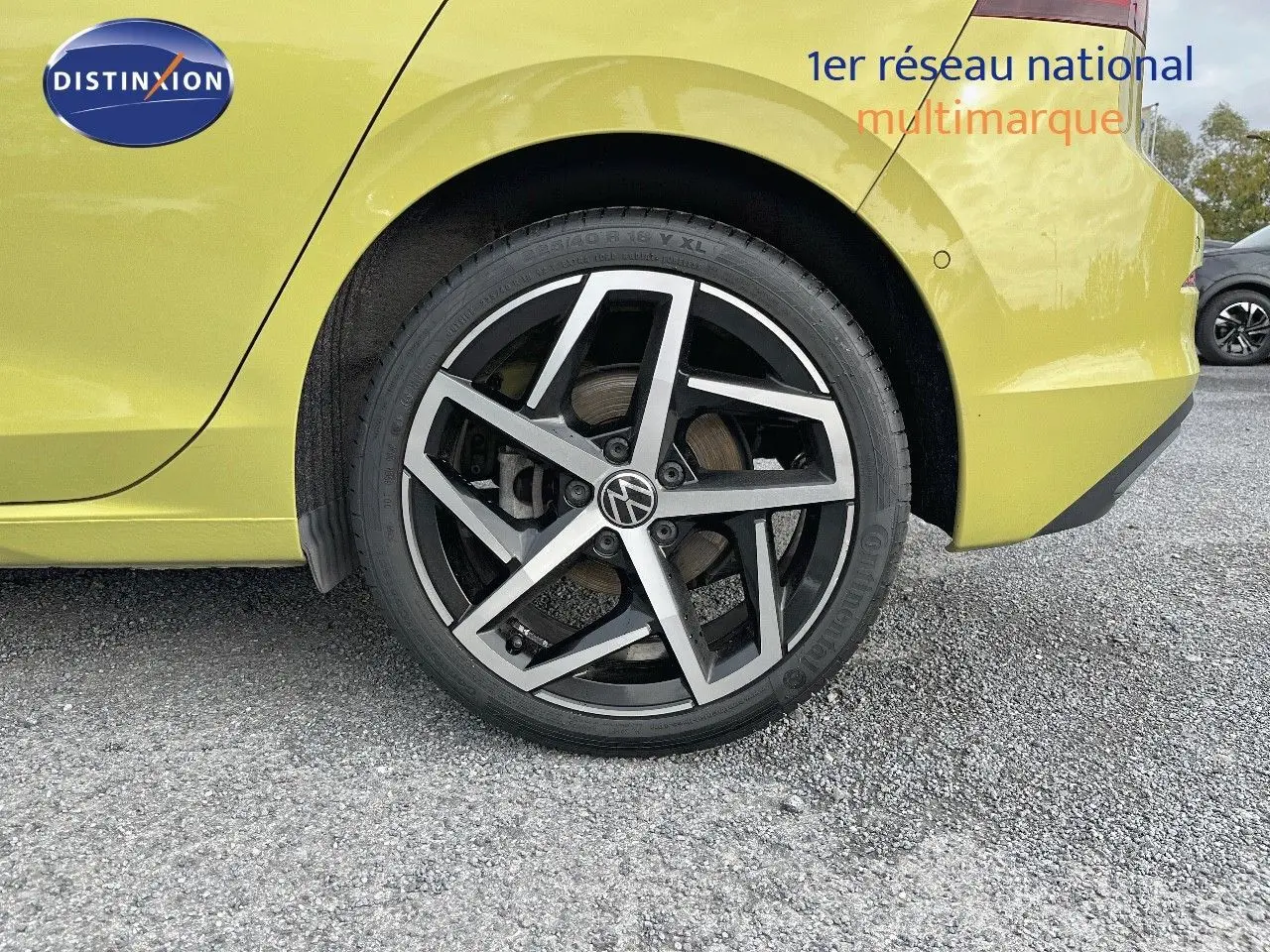 Gros plan sur la roue arrière droite d'une Volkswagen Golf jaune 2020 avec jante alliage noire et argentée.