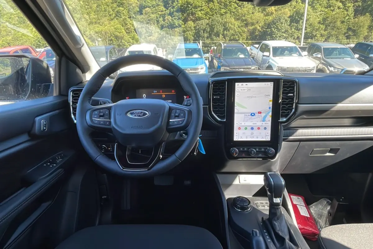 Intérieur du Ford Ranger 2025 noir shadow, vue frontale du poste de conduite avec écran tactile et volant multifonction.