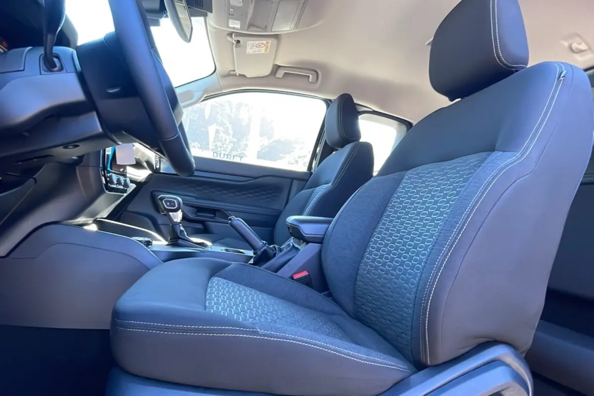 Intérieur du Ford Ranger 2025, vue côté conducteur sur les sièges tissu gris avec coutures blanches et console centrale.