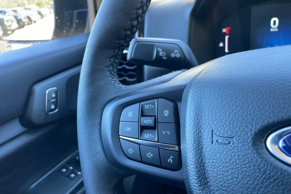 Gros plan sur le volant noir du Ford Ranger 2025, montrant les commandes de régulateur et audio côté gauche.