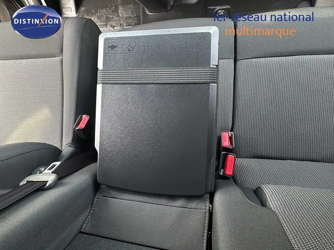 Détail de la banquette arrière avec tablette rabattable et ceintures rouges dans un Citroën Jumpy Fourgon gris titane.