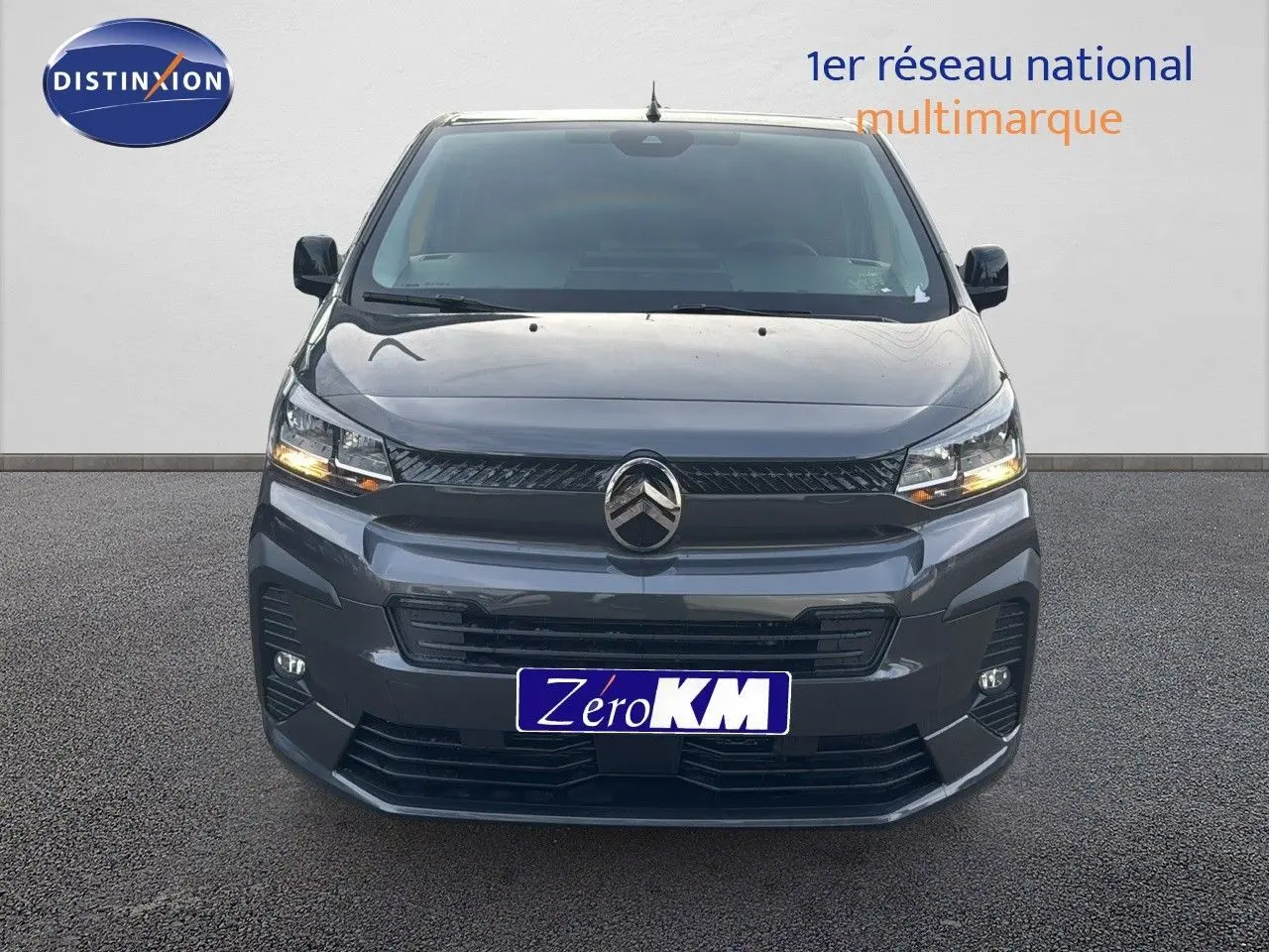 Vue frontale d'un Citroën Jumpy Fourgon XL gris titane métal avec phares allumés sur fond neutre.