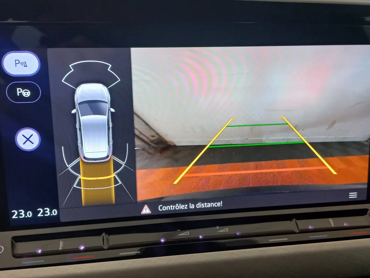 Affichage écran tactile de recul avec vue aérienne et guidage de trajectoire dans une Volkswagen Golf bleue 2022