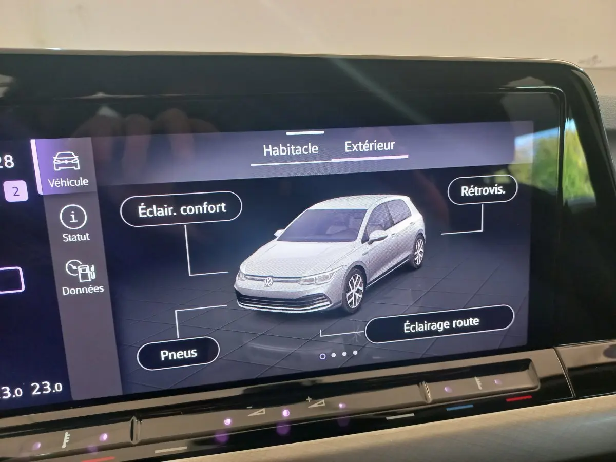 Écran tactile affichant une Volkswagen Golf blanche en 3/4 avant avec options éclairage et pneus visibles