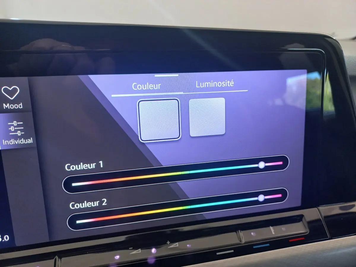 Écran tactile intérieur de la Volkswagen Golf bleu 2022 affichant les réglages de couleur et luminosité de l'ambiance lumineuse.