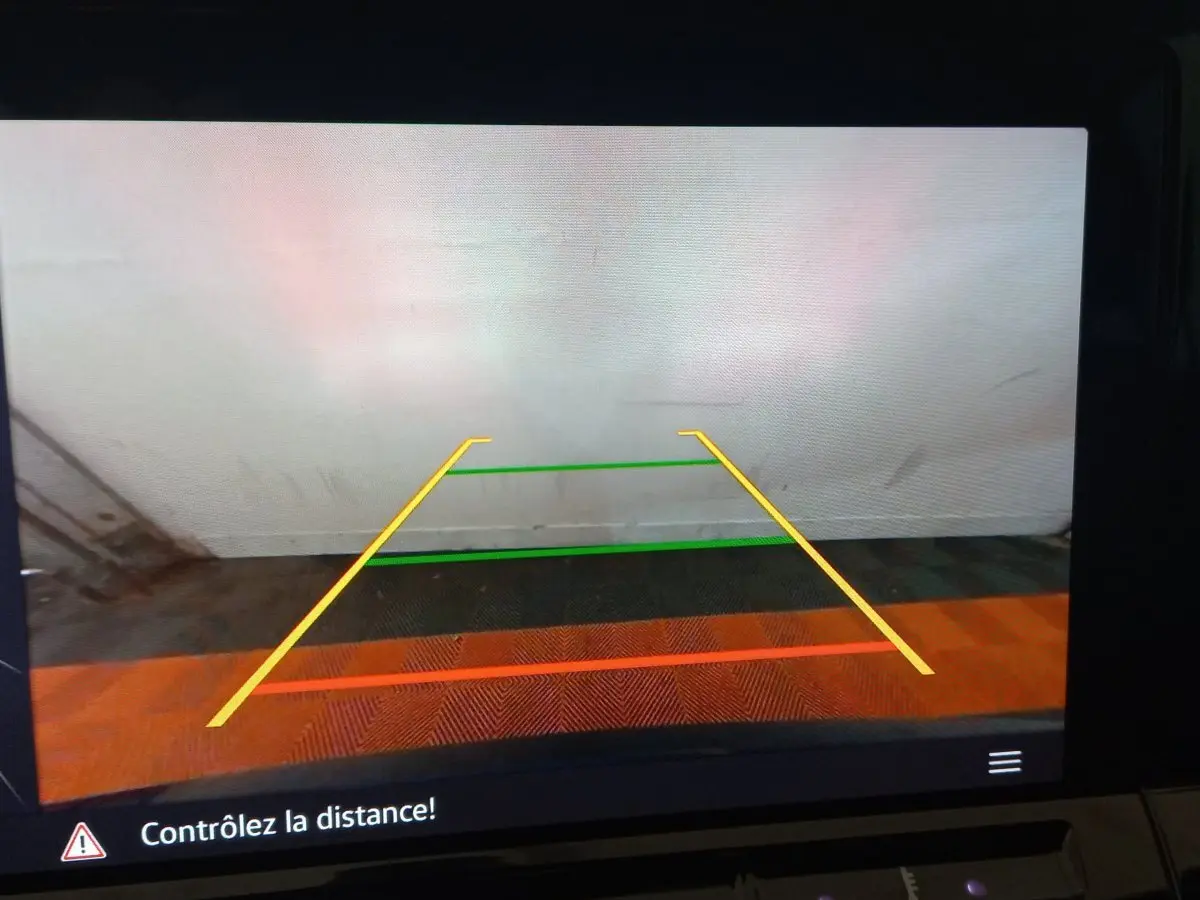 Affichage caméra de recul de la Volkswagen Golf 2022 montrant les lignes de guidage colorées sur fond de mur blanc.