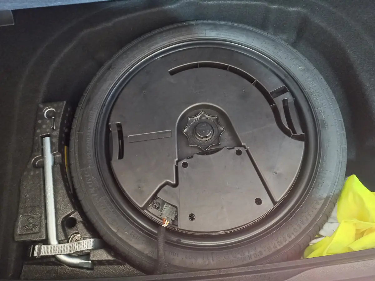 Gros plan sur la roue galette noire et les outils de secours dans le coffre d'une Volkswagen Golf bleue 2022