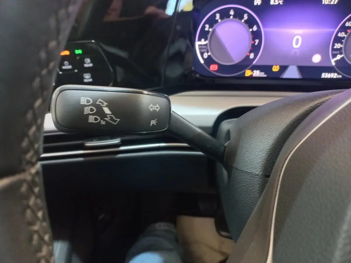 Gros plan sur la commande des feux et clignotants à gauche du volant dans une Volkswagen Golf bleue de 2022.