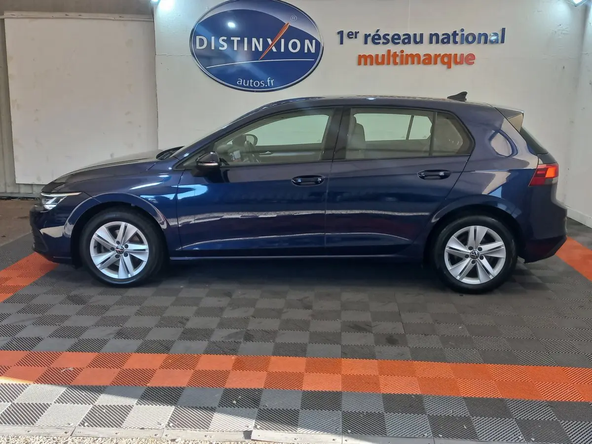 Profil côté gauche d'une Volkswagen Golf 1.5 bleu foncé, avec jantes alliage et feux arrière LED visibles.