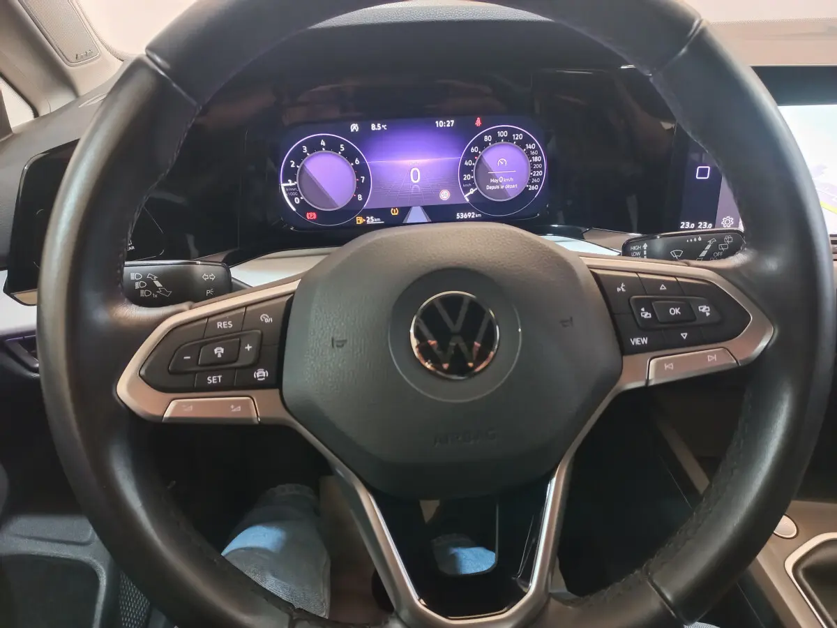 Vue intérieure centrée sur le volant cuir et le tableau de bord numérique de la Volkswagen Golf 2022.