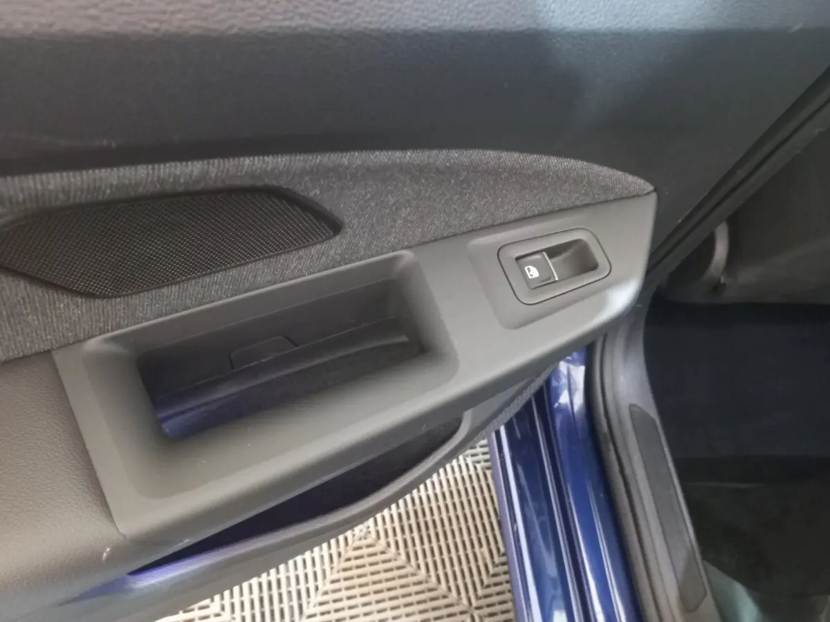 Détail de la poignée intérieure côté gauche d'une Volkswagen Golf bleue 2022 avec bouton de verrouillage intégré.