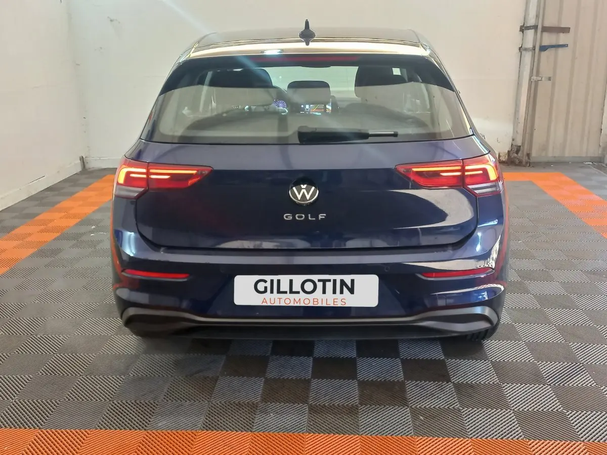 Vue arrière d'une Volkswagen Golf bleue 2022 avec feux LED allumés dans un garage intérieur.