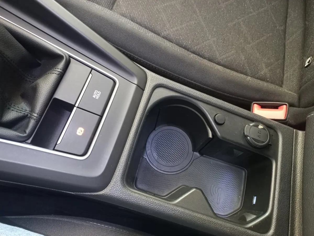 Gros plan sur la console centrale noire de la Volkswagen Golf 2022, avec zone de recharge sans fil et prise 12V visible.
