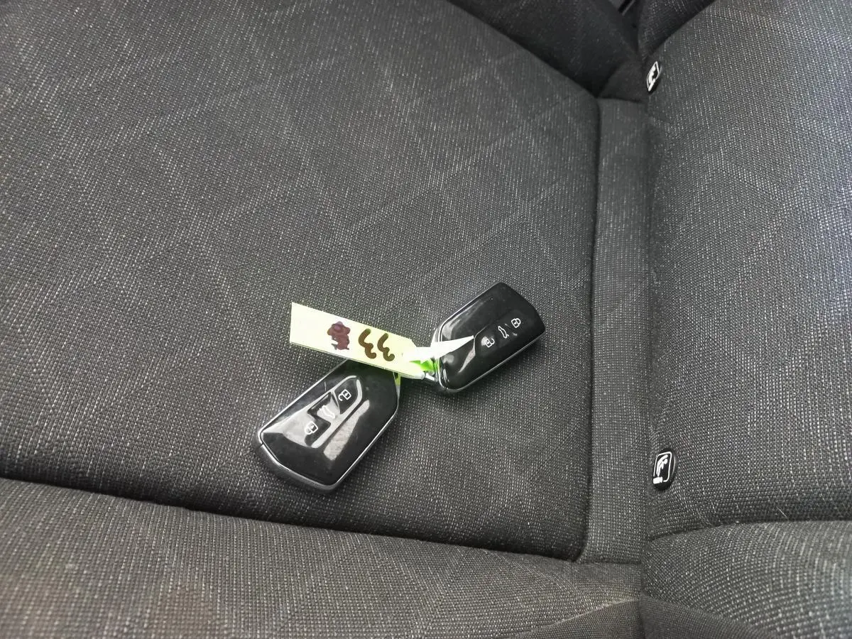 Clé de voiture Volkswagen Golf posée sur la banquette arrière en tissu gris foncé à motifs discrets.
