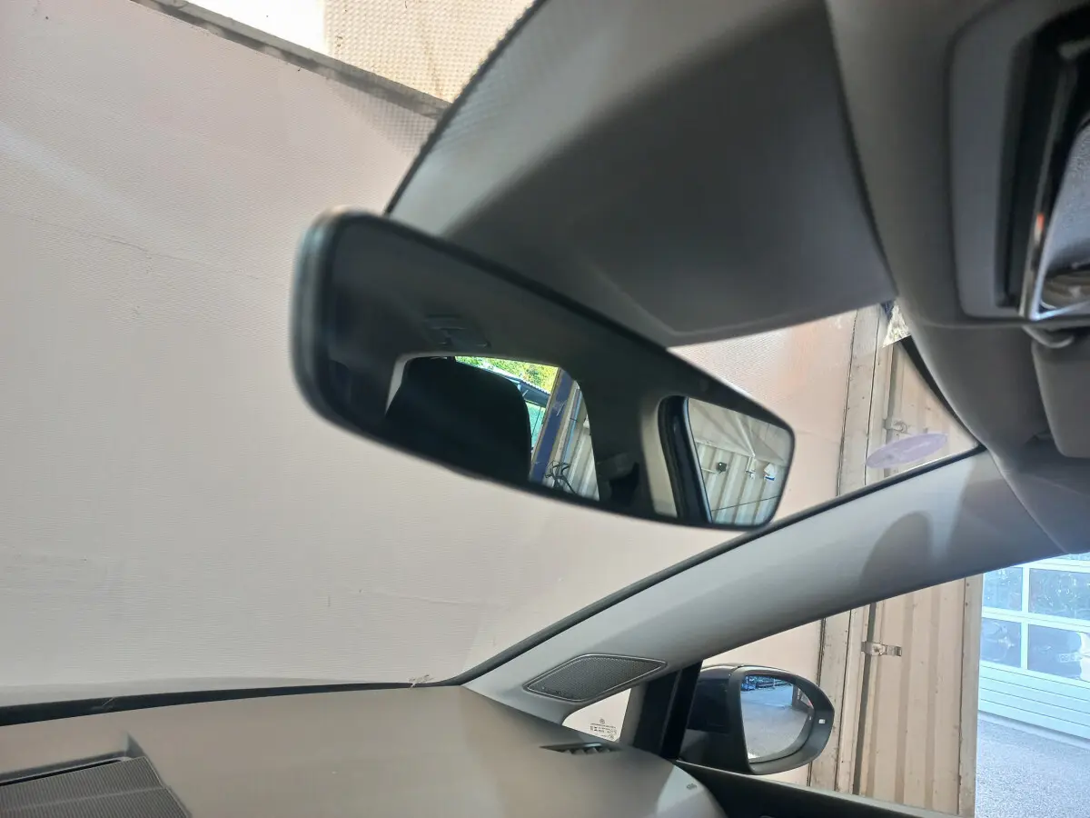 Vue intérieure côté conducteur de la Volkswagen Golf bleu 2022, avec rétroviseur central et extérieur visibles.