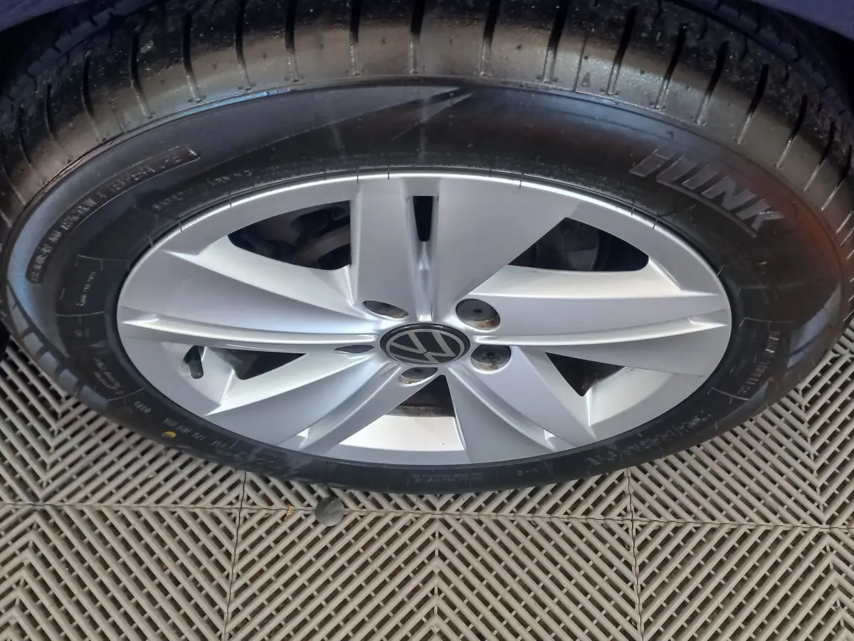 Gros plan sur la jante argentée avec logo Volkswagen d'une Golf bleu, vue du dessus sur le pneu noir.