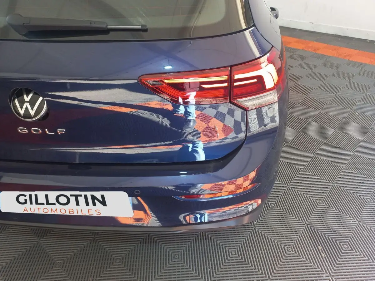 Vue arrière droite d'une Volkswagen Golf bleue avec feux LED et logo VW bien visibles.