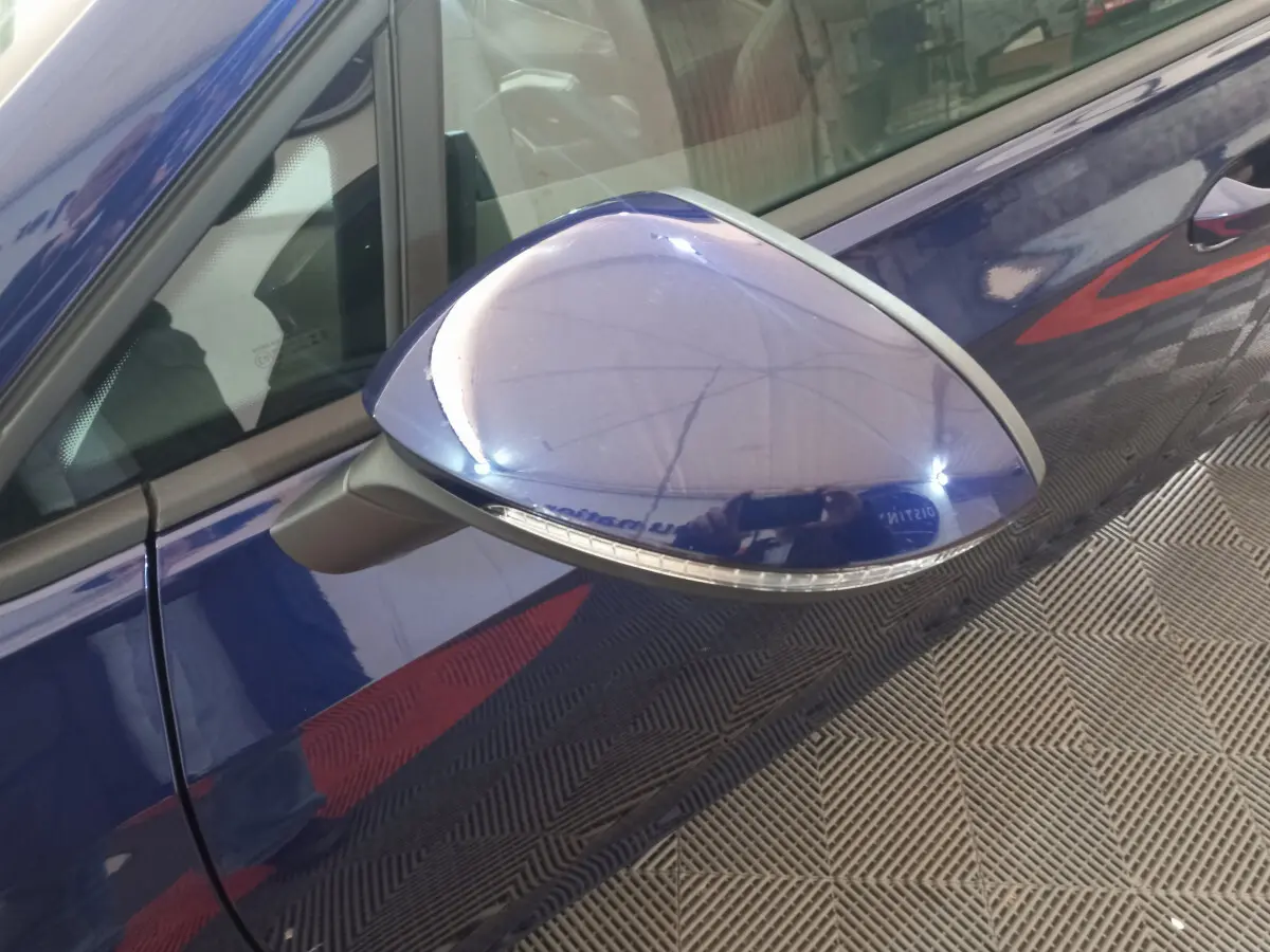 Rétroviseur côté gauche bleu brillant d'une Volkswagen Golf 2022, avec clignotant intégré visible en gros plan.