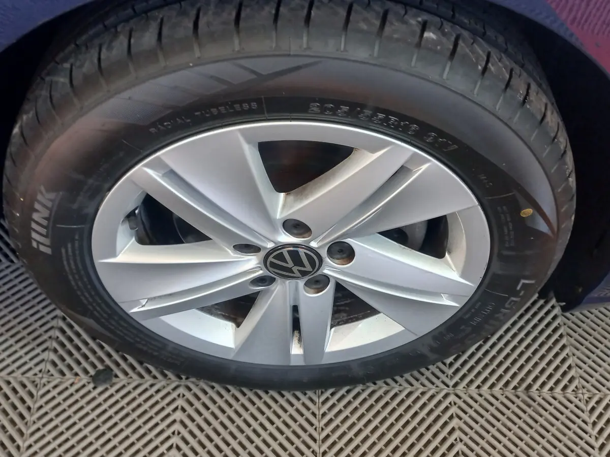 Gros plan sur la roue avant droite de la Volkswagen Golf bleu, avec jante alliage argentée et logo VW central.