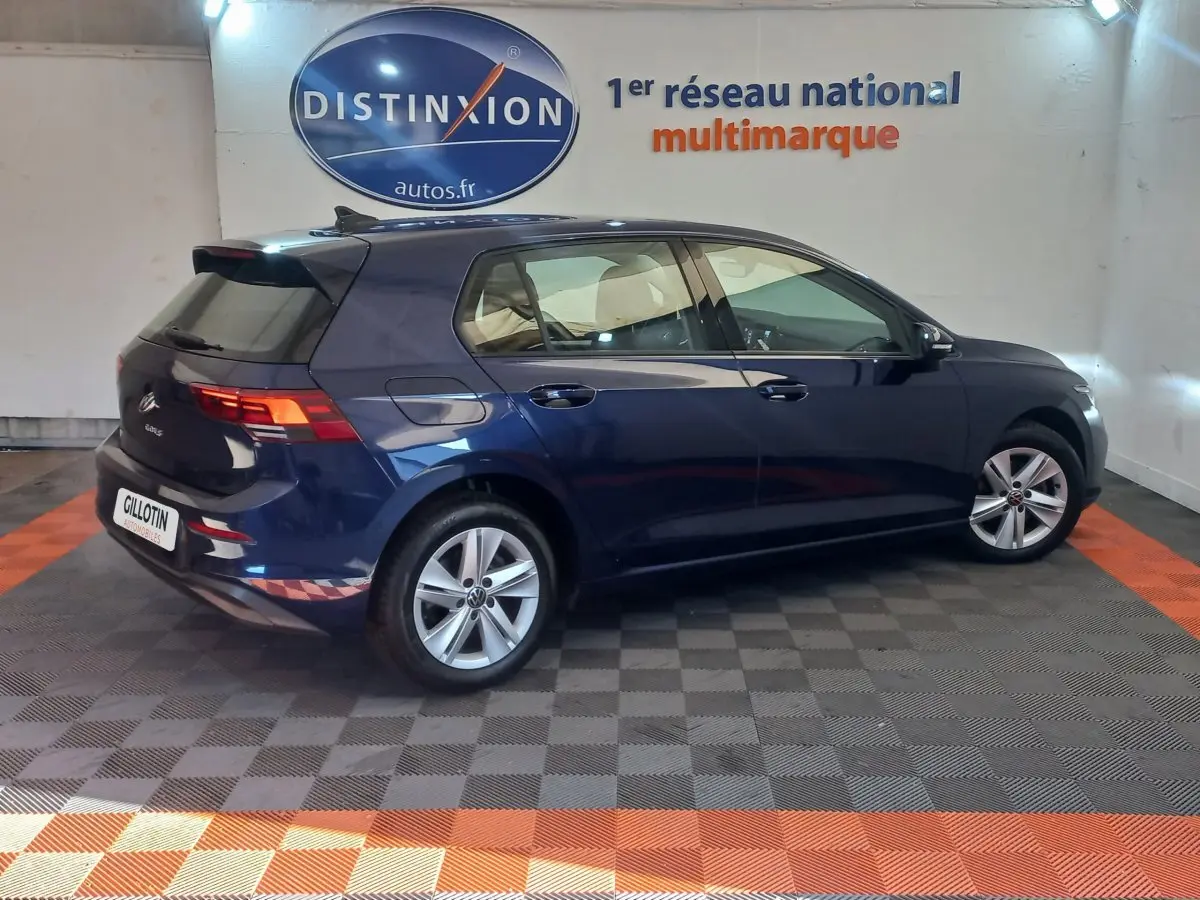 Volkswagen Golf 1.5 essence bleu vue profil côté droit en intérieur avec jantes alliage et feux arrière LED allumés