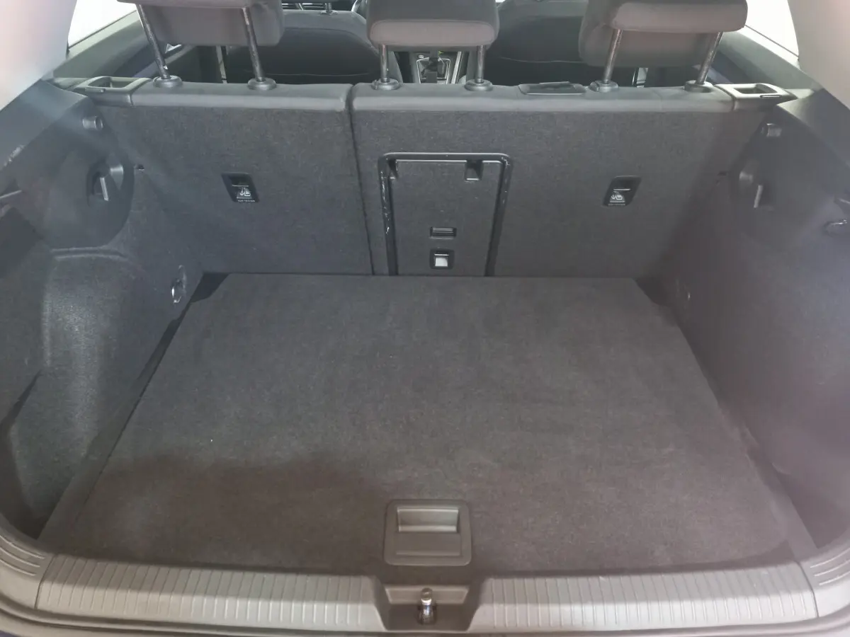 Coffre spacieux de Volkswagen Golf 2022 vu de l'arrière, revêtement intérieur gris foncé et banquette arrière rabattue partiellement.