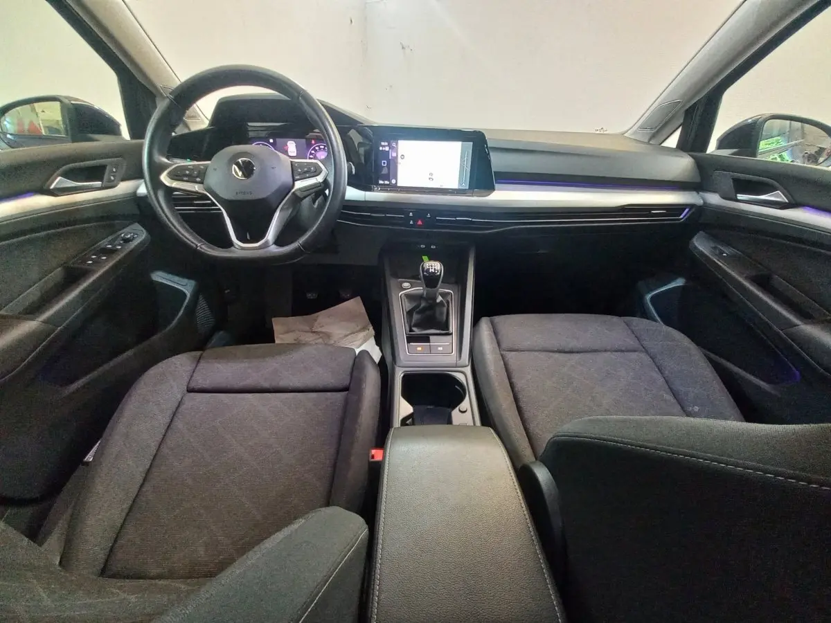Intérieur avant de la Volkswagen Golf 2022, vue frontale sur tableau de bord noir avec écran tactile et volant multifonctions.