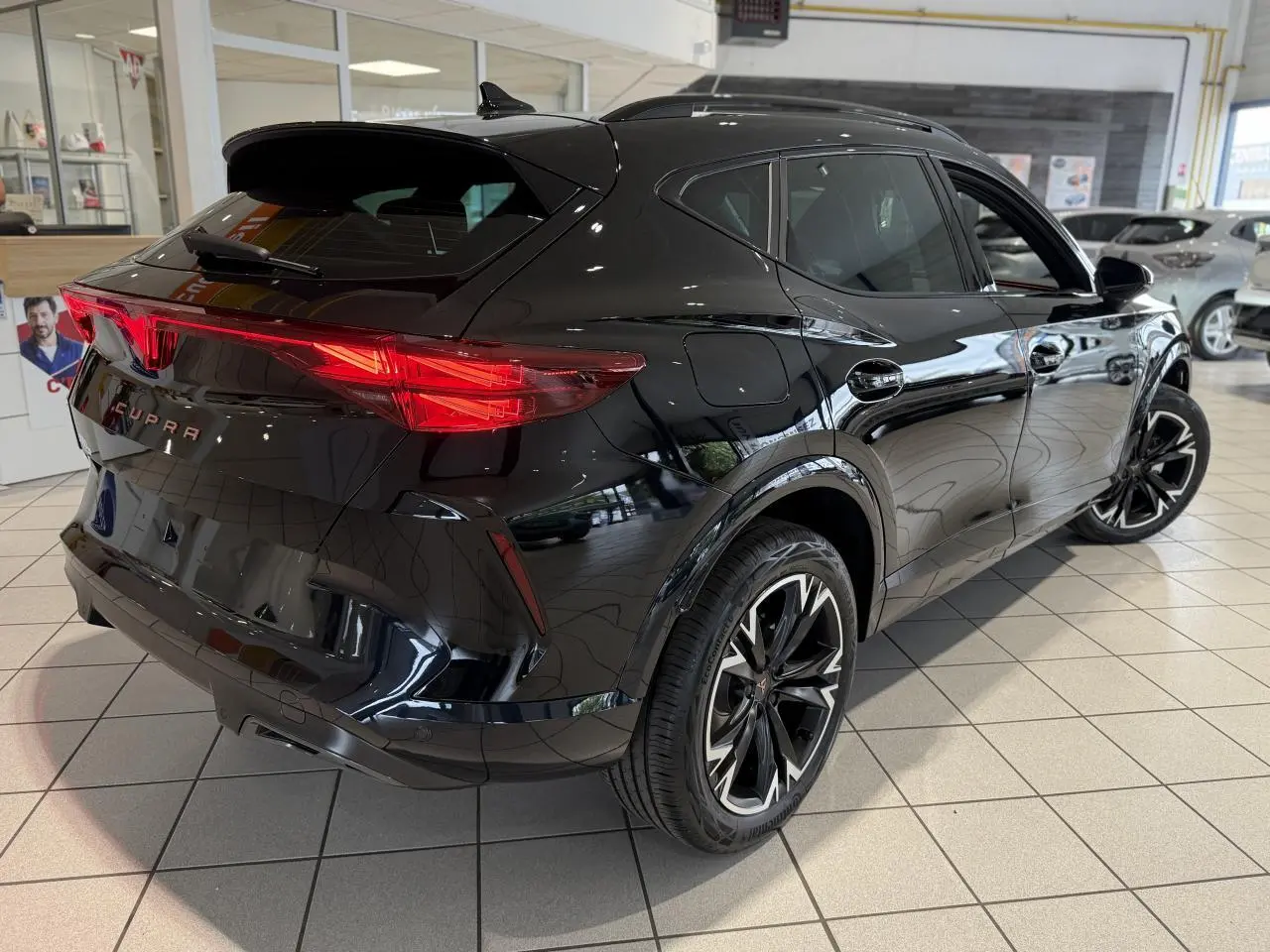Vue 3/4 arrière droite d'une CUPRA Formentor noire Night avec feux arrière Tri-LED et jantes alliage 18'' au showroom.