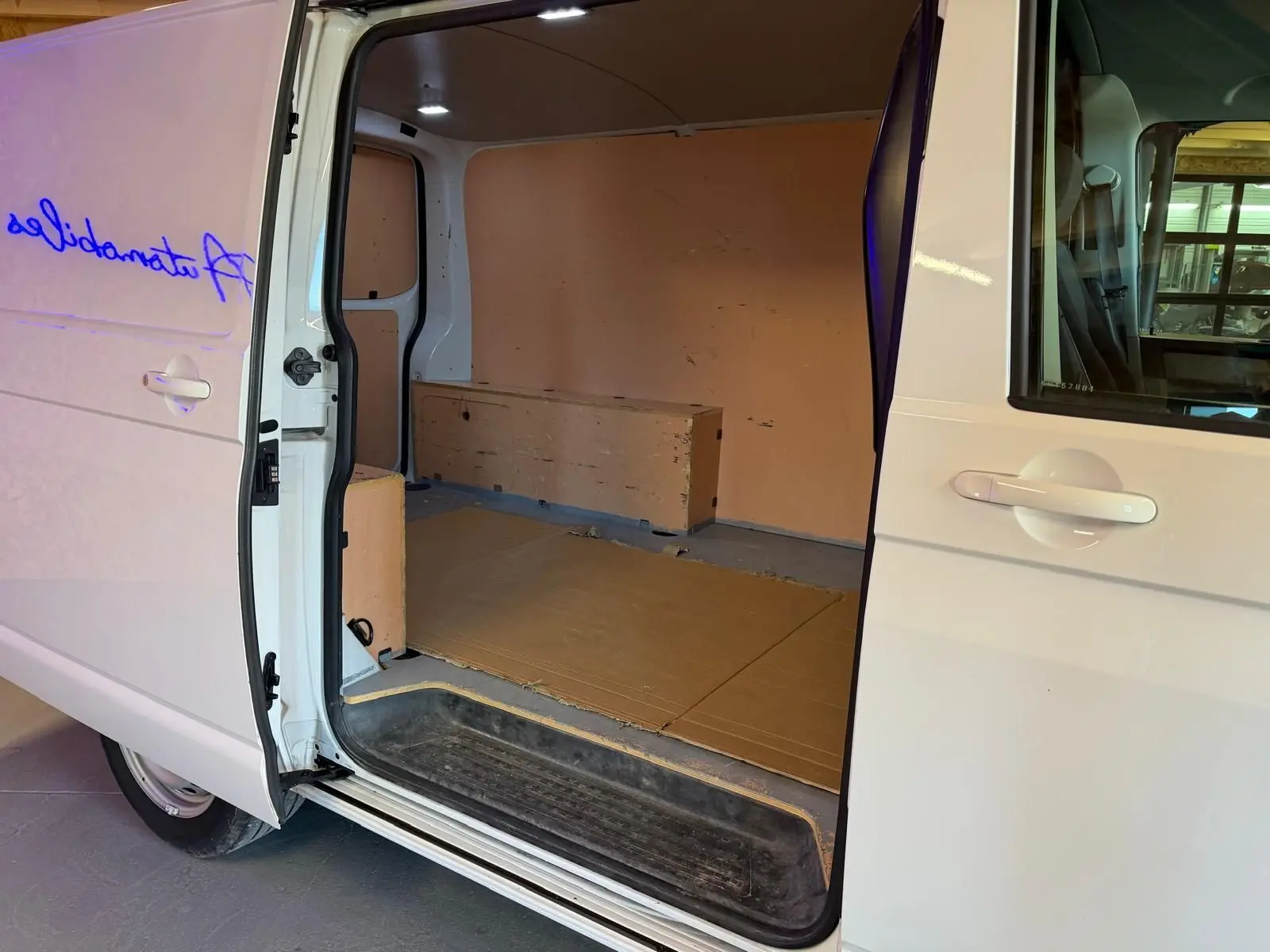 Vue latérale gauche du Volkswagen Transporter blanc 2019 avec porte coulissante ouverte montrant l'espace de chargement vide.