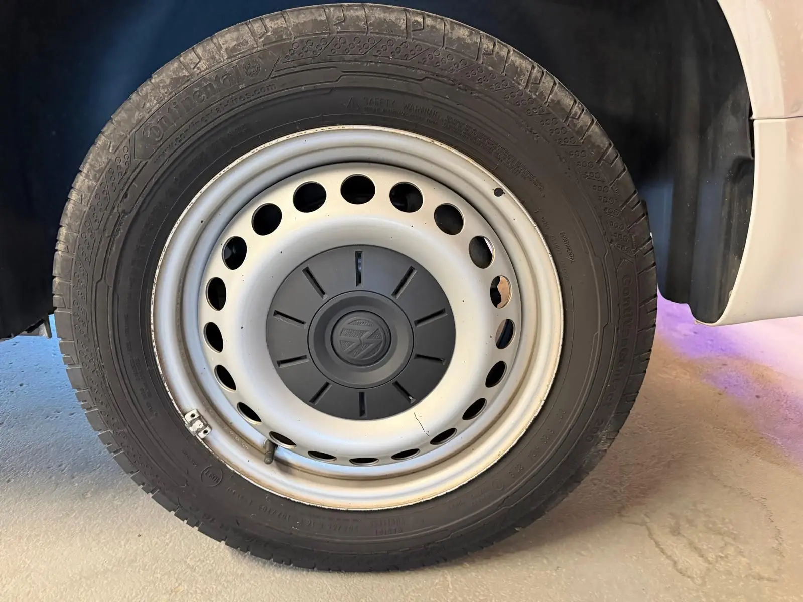 Gros plan sur la roue avant droite du Volkswagen Transporter blanc, avec jante acier et logo VW au centre.