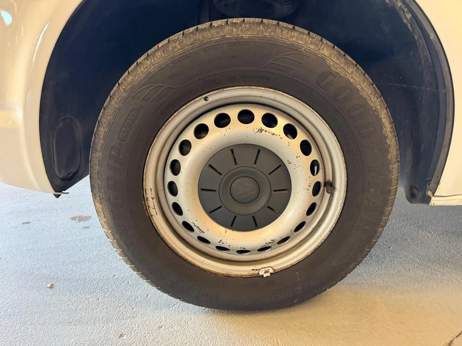 Gros plan sur la roue avant droite blanche du Volkswagen Transporter 2019 avec jante acier et logo VW central.