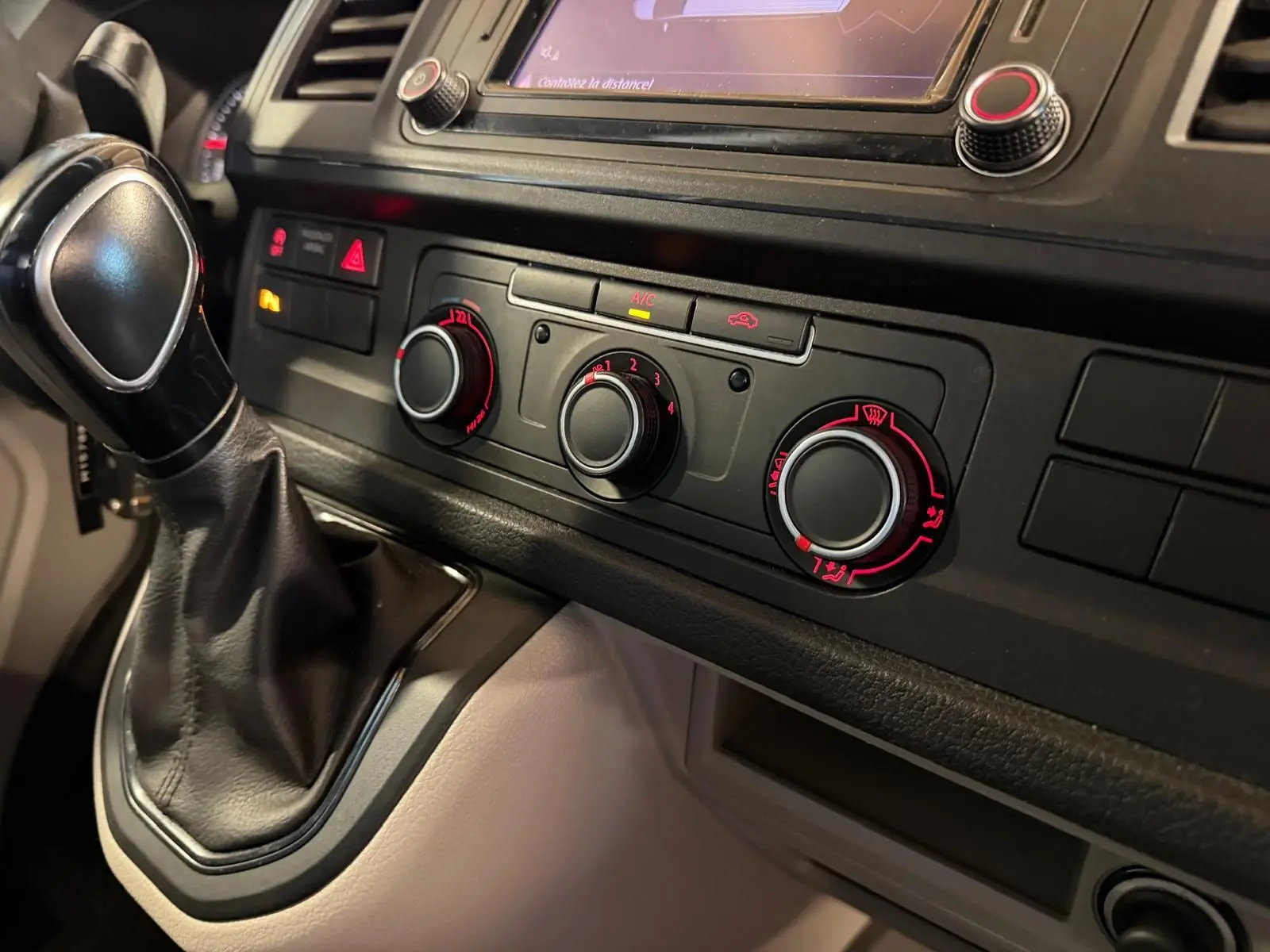 Vue rapprochée de la console centrale noire du Volkswagen Transporter 2019 avec levier de vitesse et commandes de climatisation.
