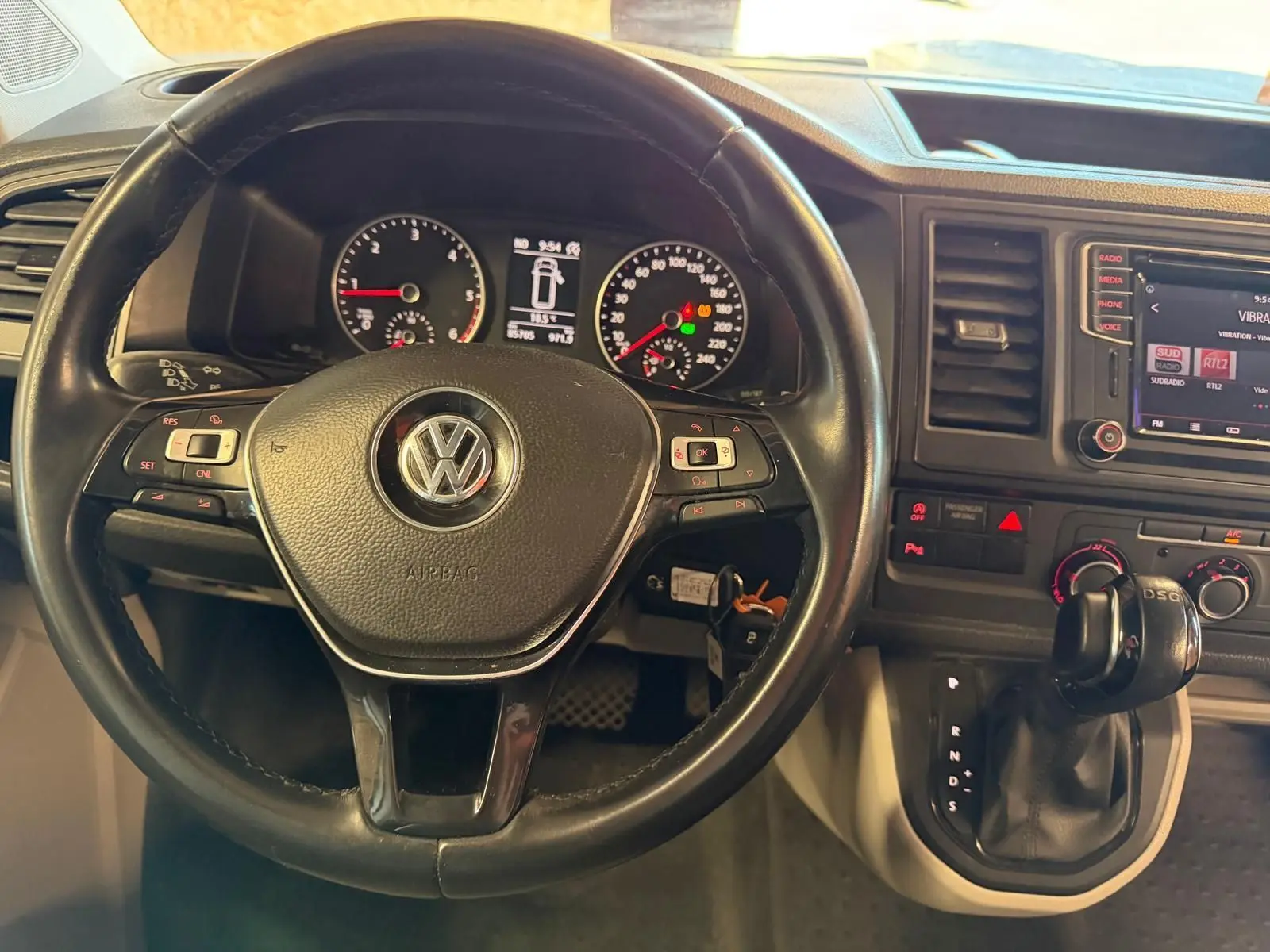 Vue rapprochée du volant noir et du tableau de bord du Volkswagen Transporter blanc, avec levier de vitesse DSG visible.