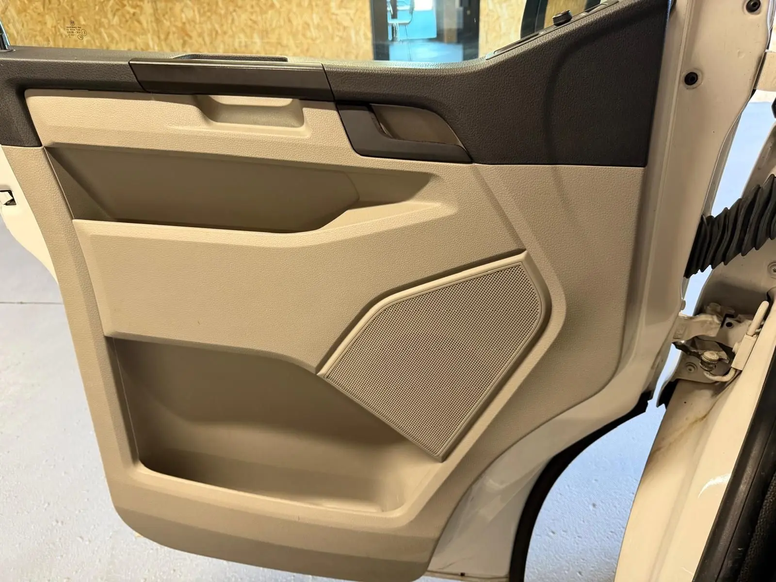 Vue rapprochée de la porte intérieure beige et noire côté droit du Volkswagen Transporter blanc de 2019.