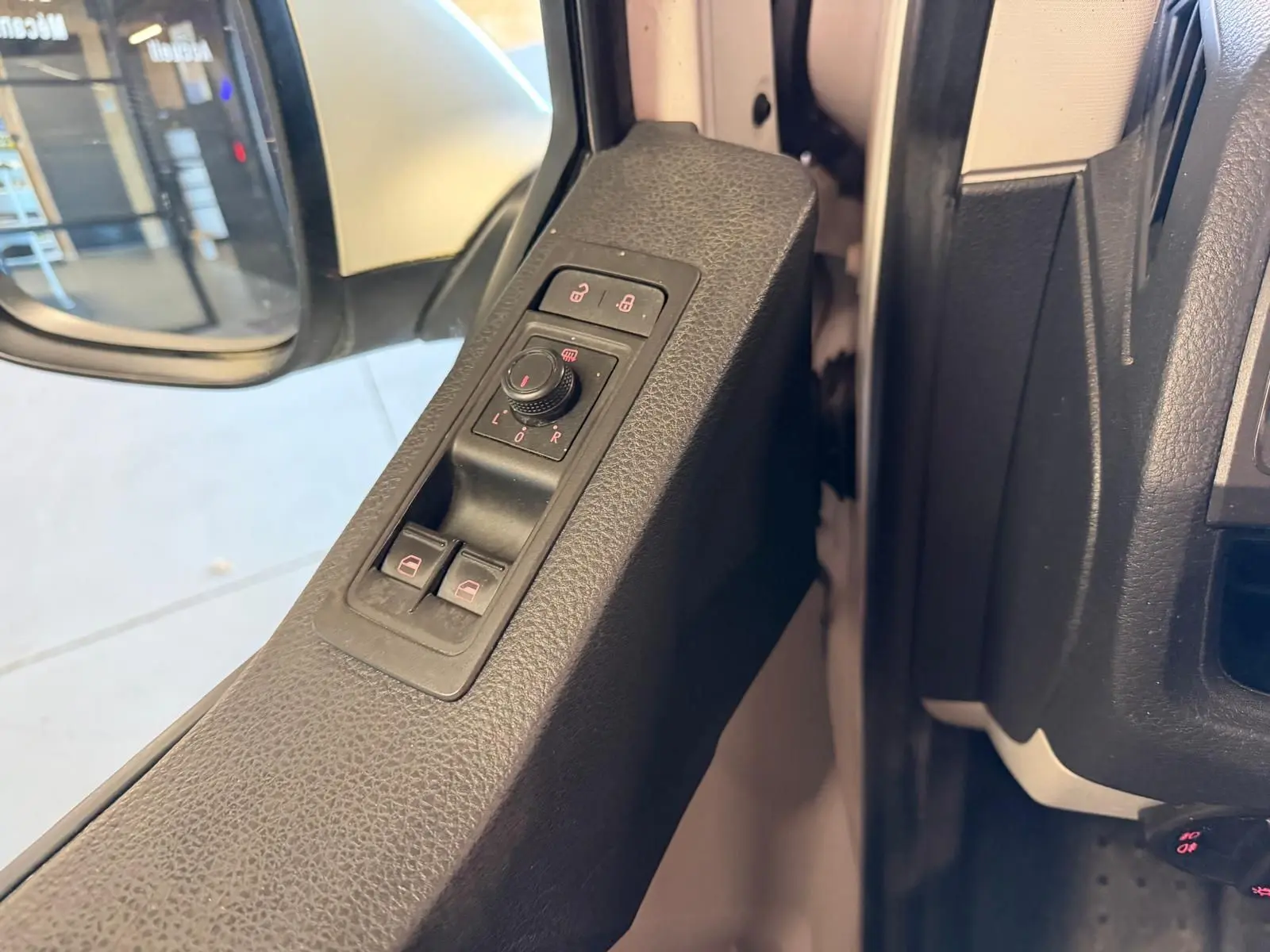Vue rapprochée de la commande des rétroviseurs et vitres côté gauche du Volkswagen Transporter blanc 2019.