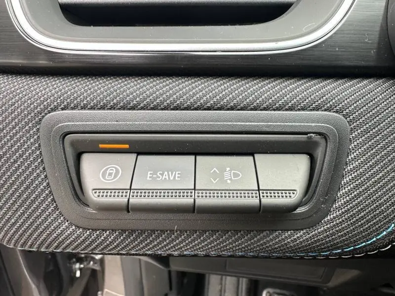 Gros plan sur les boutons de commande E-SAVE et réglage des phares du tableau de bord du Renault Captur Gris Cassiopée/Noir Etoilé 2026.