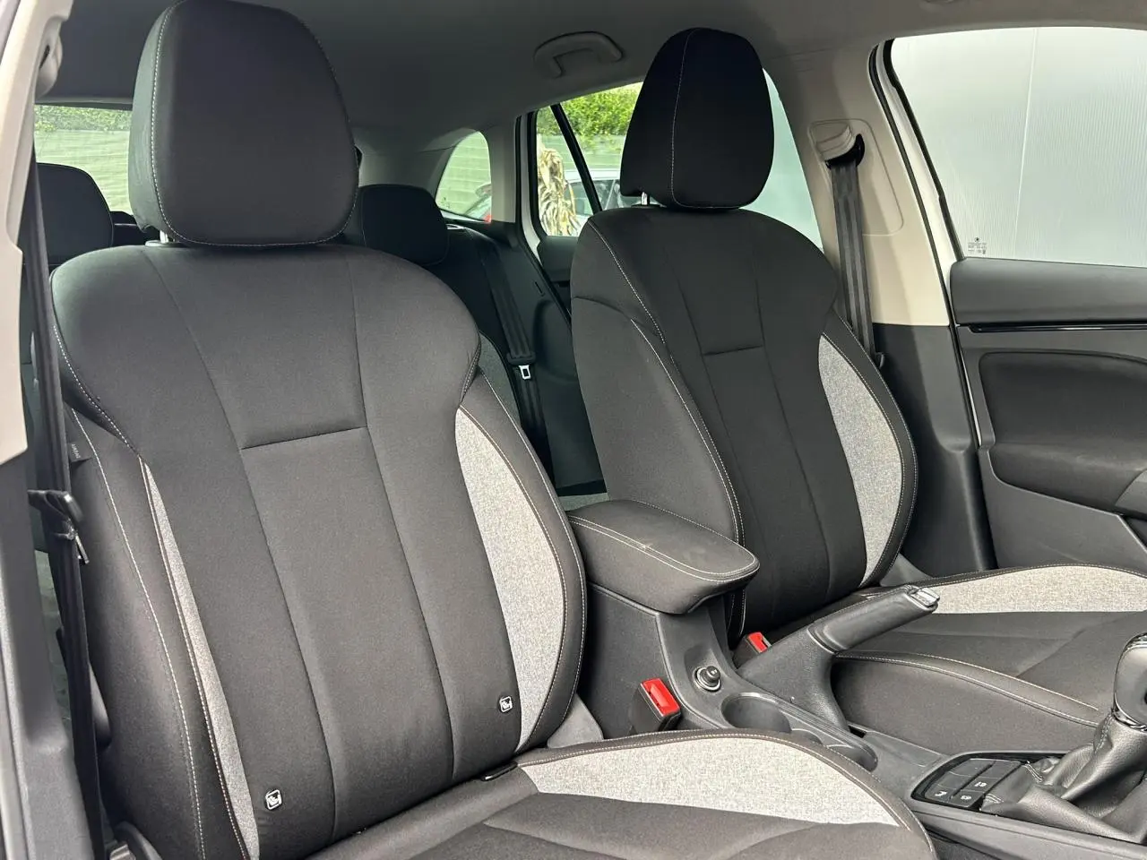 Vue intérieure des sièges avant en tissu noir et gris avec accoudoir central sur une Skoda Scala 2025.