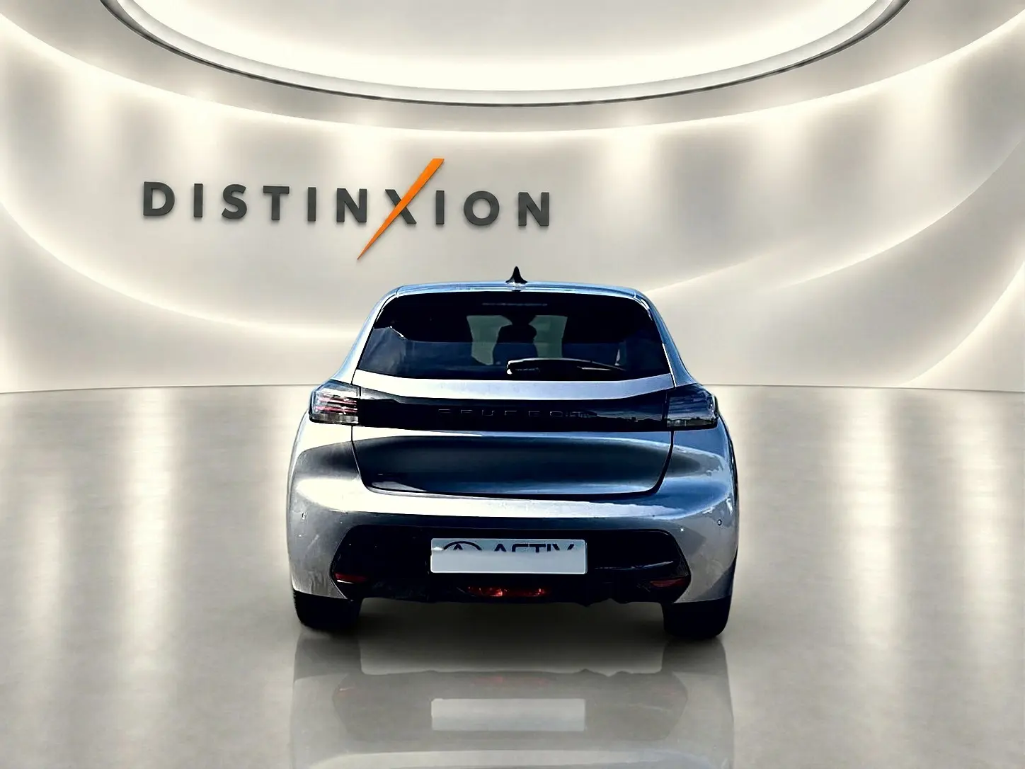 Vue arrière d'une Peugeot 208 gris artense 2025 dans un showroom avec éclairage doux et logo Distinxion en arrière-plan.
