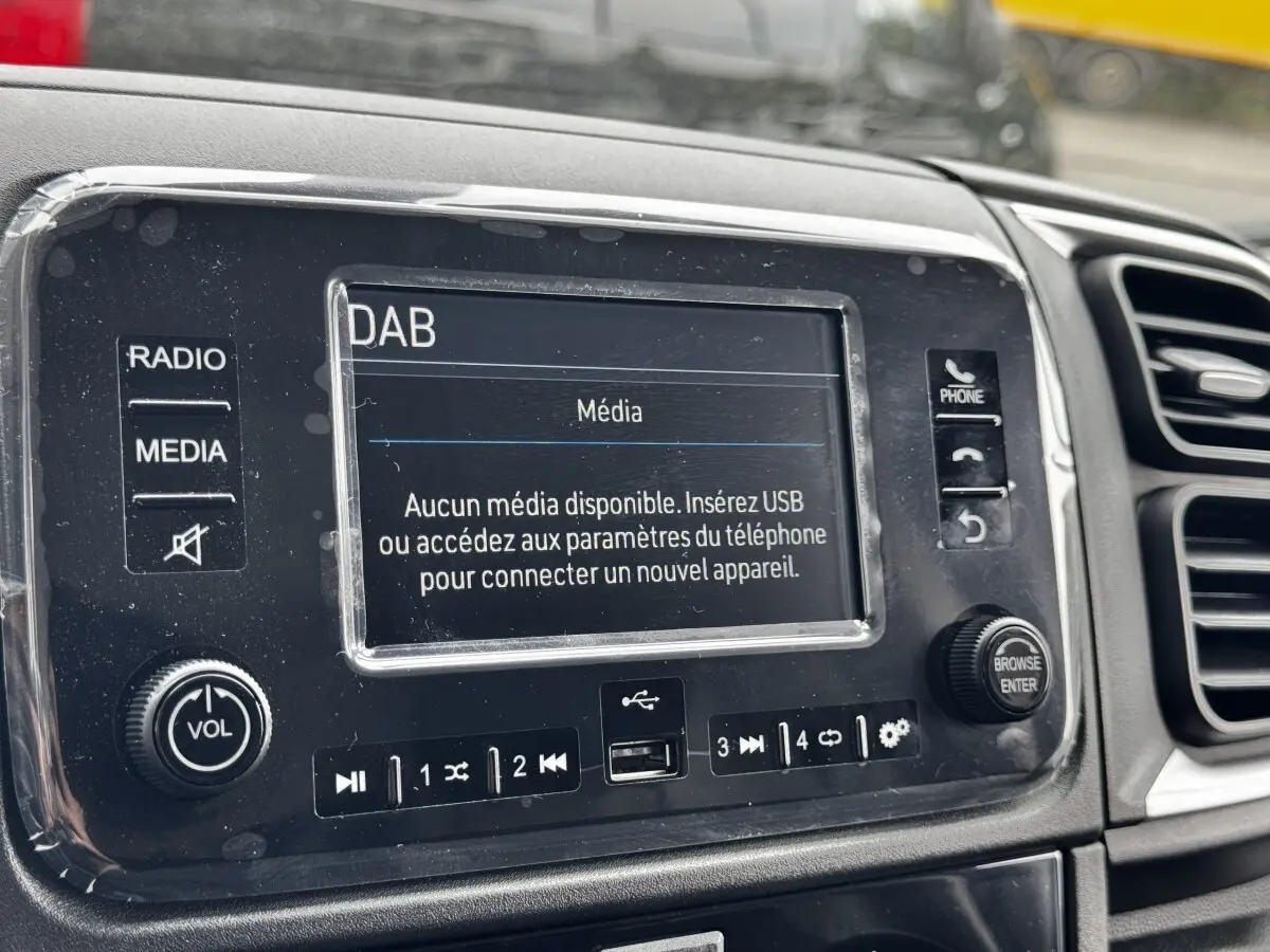 Gros plan sur l’écran tactile multimédia du tableau de bord du Peugeot Boxer Fourgon blanc, avec commandes et port USB visibles.
