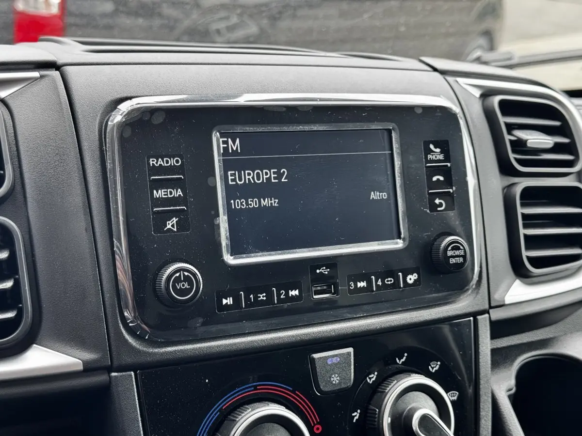 Gros plan sur l’écran tactile central du tableau de bord noir du Peugeot Boxer Fourgon blanc, affichant une radio FM.