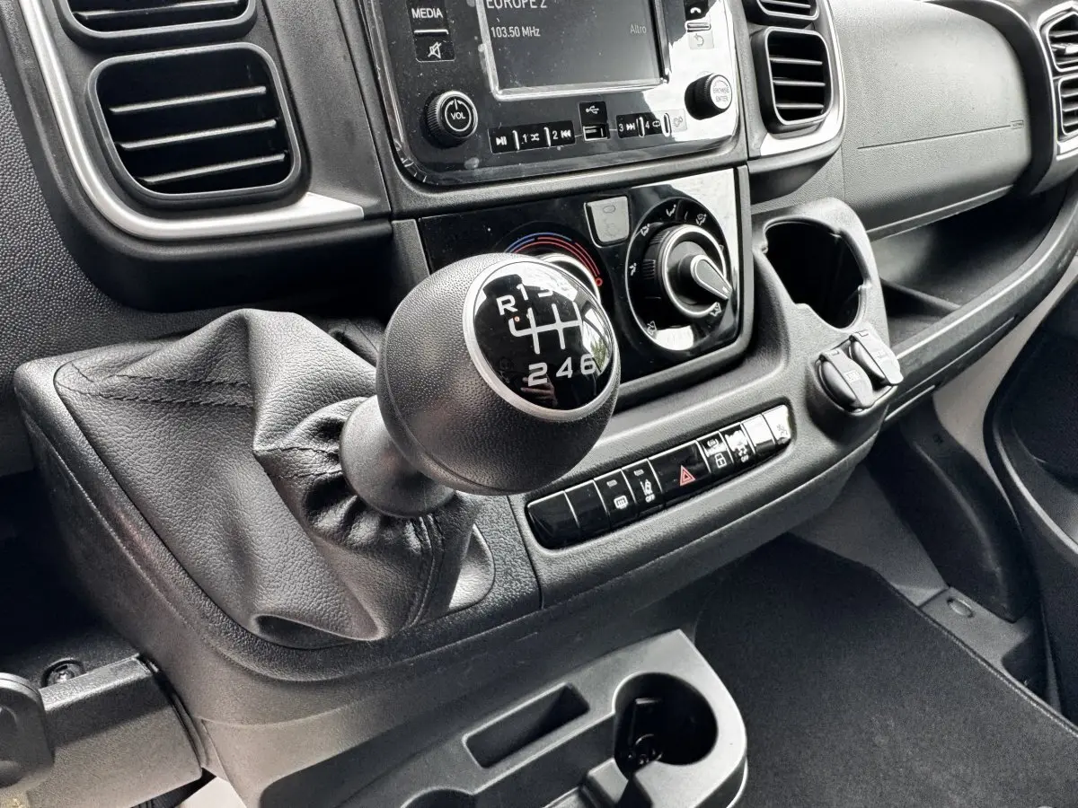 Gros plan sur la boîte manuelle et la console centrale noire du Peugeot Boxer Fourgon L2H2 2026, intérieur fonctionnel.