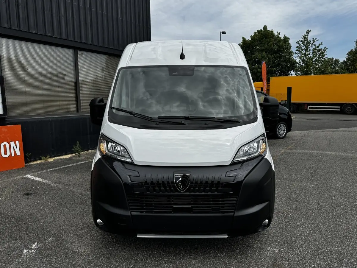 Vue avant d’un Peugeot Boxer Fourgon blanc avec calandre noire et logo lion bien visible, stationné en extérieur.