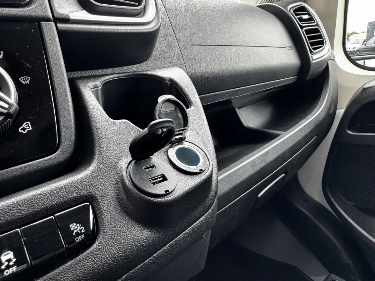 Vue intérieure côté passager du tableau de bord noir avec prise USB ouverte du Peugeot Boxer Fourgon blanc L2H2 2026.